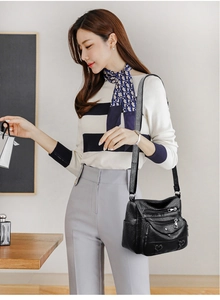 Detail view of black soft leather crossbody bag with multiple zipper pockets on model