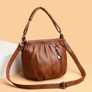 Detail of vintage brown PU leather bucket bag with pleated design and metallic zipper tassel