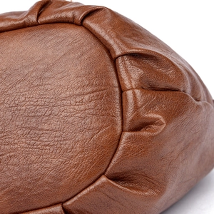 Macro shot of litchi texture PU leather and pleated stitching details on a brown bucket bag
