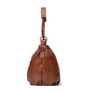 Close-up of caramel PU leather bucket bag showing soft texture and metal zipper detail