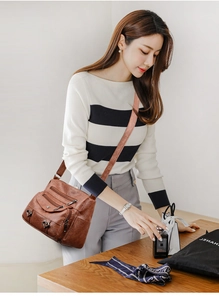 Close-up of brown multi-pocket leather crossbody bag featuring heart charms and vintage texture