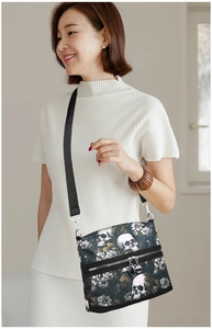 Detail of dual zipper compartments and adjustable strap on skull floral print bag