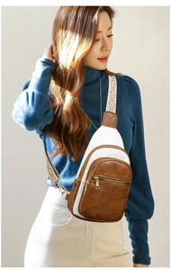 Detail of crossbody bag featuring multi-zipper layers and a patterned wide strap