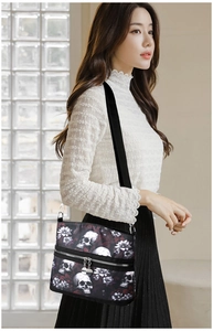 Detail of crossbody bag featuring skull and floral prints with dual metal zipper pockets