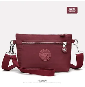 Detailansicht der weinroten Nylon-Umhängetasche mit Reißverschluss und Sport-Logo