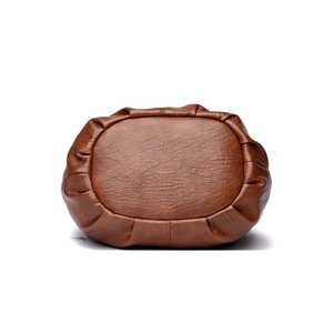 Detail view of the oval bottom structure and stitched pleats on this brown PU leather bag