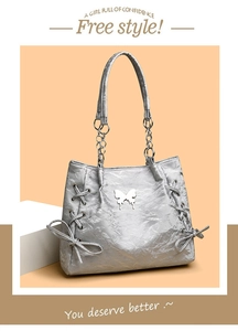 Silver tote bag with metallic butterfly emblem and side drawstring ribbon details