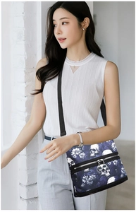 Detailed view of the crossbody bag with skull floral print and multiple zipper pockets