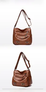Detail view of multi-pocket brown leather crossbody bag with heart-shaped metal accents