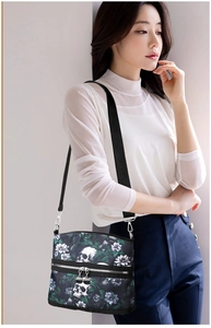 Close-up of skull and flower print on shoulder bag with silver metallic zippers