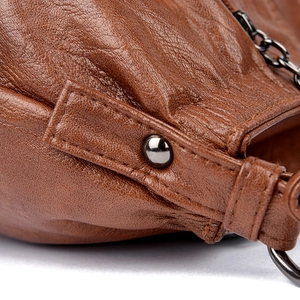 Close-up of brown pebbled leather texture with metal rivets and sturdy stitching