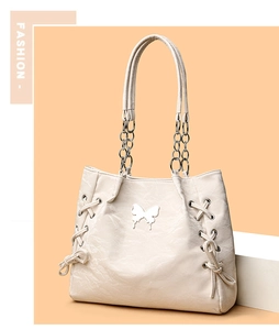 Detail of cream tote bag with butterfly metal clasp and side drawstring texture