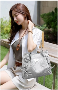 Detail of silver metallic tote bag with butterfly charm and crisscross drawstring accents