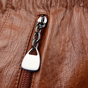 Macro detail of brown litchi pattern leather with silver metal zipper on a bucket bag