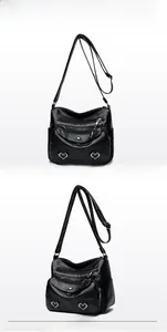 Detail view of black multi-pocket crossbody bag with soft faux leather and heart buckle