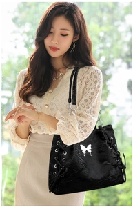 Detail of black leather tote bag with white butterfly motif and side lace-up eyelets