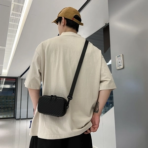 Fashionable black hard-shell crossbody phone bag with textured surface and shoulder strap