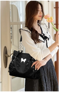 Detail view of black tote bag featuring silver butterfly ornament and drawstring sides