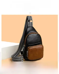Detail of black crossbody bag with brown pocket and patterned strap on white props