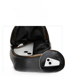 Close-up of black lychee grain leather sling bag showing spacious front pocket and main interior