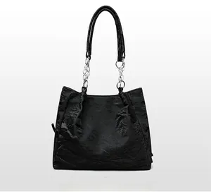 Rear view of black pleated tote bag with leather and silver chain shoulder strap