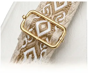 Detail of adjustable golden metal buckle and ethnic geometric woven shoulder strap on white bag