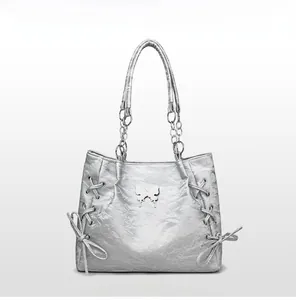 Detail of silver tote bag with textured faux leather and metal butterfly emblem