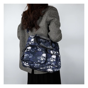 Model wearing a large skull print tote bag over a grey herringbone wool coat in studio