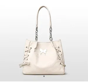 Detail of off-white tote bag showing silver butterfly ornament and woven ribbon sides