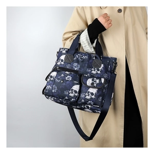 Detail of skull print tote bag with dual front pockets and adjustable strap shown on model