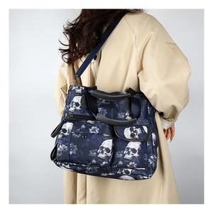 Detail view of large skull and floral print tote bag with multiple pockets on shoulder