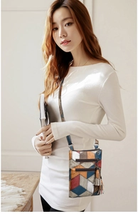 Detail of colorful geometric patchwork PU leather shoulder bag with decorative tassel