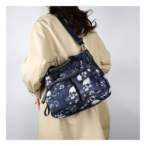 Detail of skull print tote bag featuring multiple zip pockets and wide strap on model