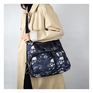Detail of navy blue skull floral tote bag showing multi-pocket design on beige trench coat