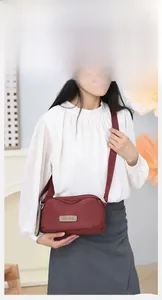 Close-up of waterproof burgundy nylon shoulder bag featuring the metallic brand logo