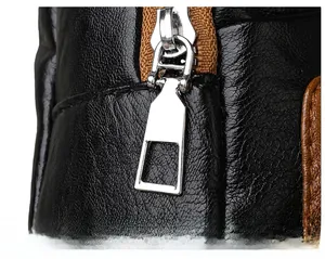 Macro detail of black pebble leather shoulder bag showing silver zipper and brown tape