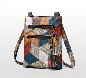 Detail view of colorful PU leather crossbody bag with dual zippers and tassel accents