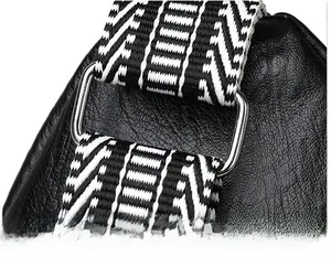 Detail of lychee pattern leather bag with silver hardware and striped fabric strap