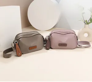 Waterproof nylon shoulder bags in taupe and pink with adjustable wide straps for travel