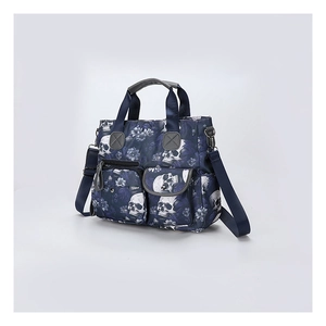Detail of gothic skull floral print tote bag with dual front pockets and shoulder strap