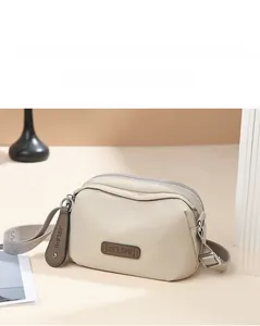Detail view of beige multi-layer oxford fabric shoulder bag with high-quality zippers