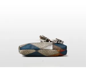 Detail view of the colorful leather patchwork base with bold white stitching and tassels