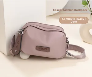 Close-up of pink water-resistant nylon shoulder bag with a branded leather logo patch