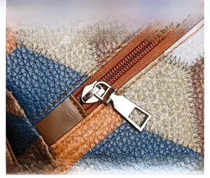 Detail of color-block lychee grain leather stitching and silver metal zipper puller