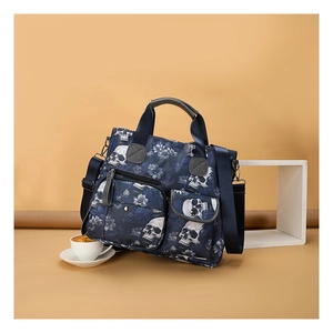 Close-up of skull and floral print tote bag with multiple zip pockets and adjustable strap