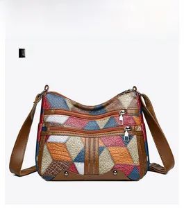 Detail view of the multi-color patchwork faux leather crossbody bag with front zippers