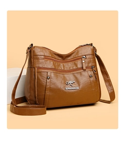 Detail view of brown textured leather crossbody bag with triple zipper pockets and metal logo