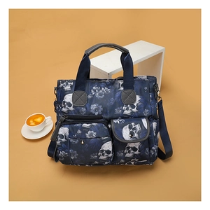 Detail of blue skull and floral tote bag showing front zipper pockets and top handles