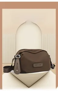 Detailed view of dark brown oxford fabric shoulder bag with silver zippers and wide strap