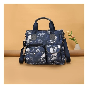 Detail of blue tote bag with skull and floral print featuring dual front zipper pockets